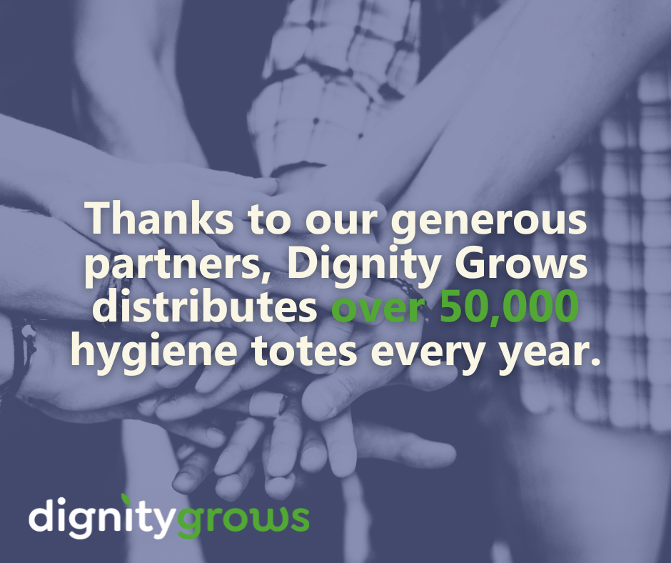 A group of people put their hands together. Text reads "thanks to our generous partners, Dignity Grows distributes over 50,000 hygiene totes every year."