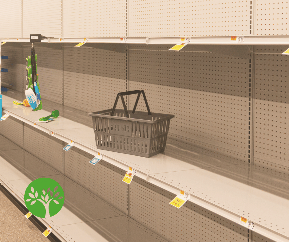 An empty hand basket sits atop cleared-off grocery store shelves